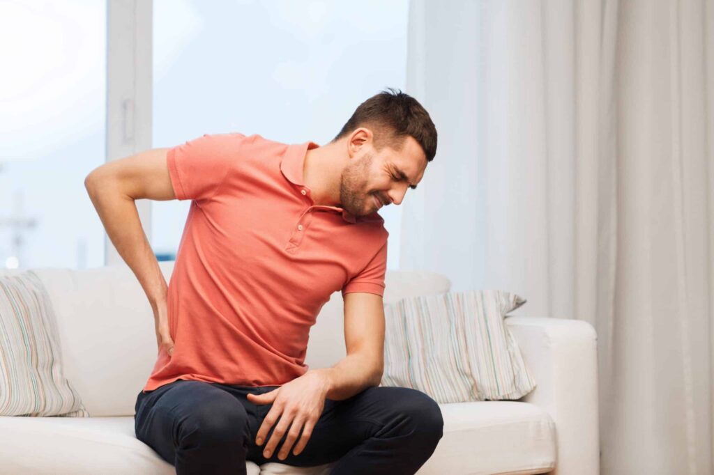 Back pain chiropractic care patient holding his lower back in pain.