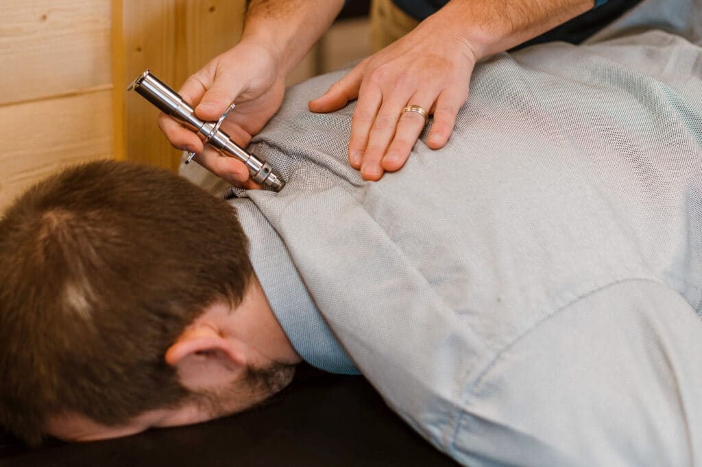 Chiropractor using a tool to adjust a patient's spine in Eau Claire.